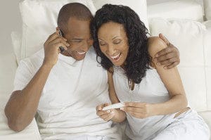 couple smiling down at pregnancy test
