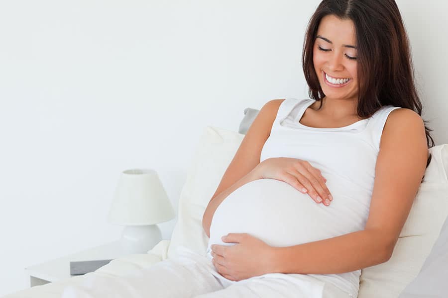 smiling woman holding pregnant belly
